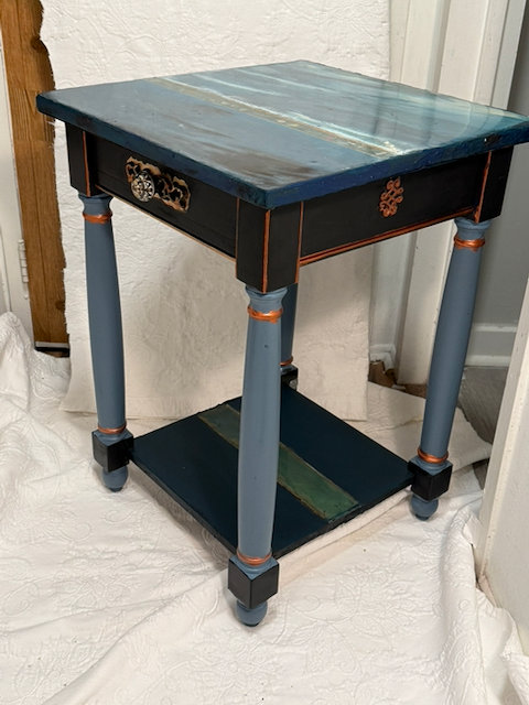 Blue side table with gold-colored detailing and a lower shelf